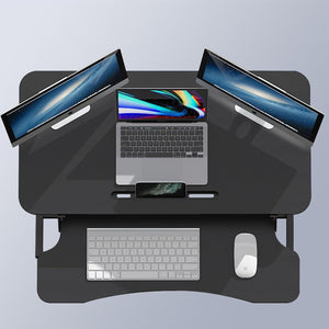 Höhenverstellbarer, schwarzer Schreibtischaufsatz in einem Anwendungsbeispiel mit zwei Bildschirmen, einem Laptop, einer Tastatur und einer Maus von oben