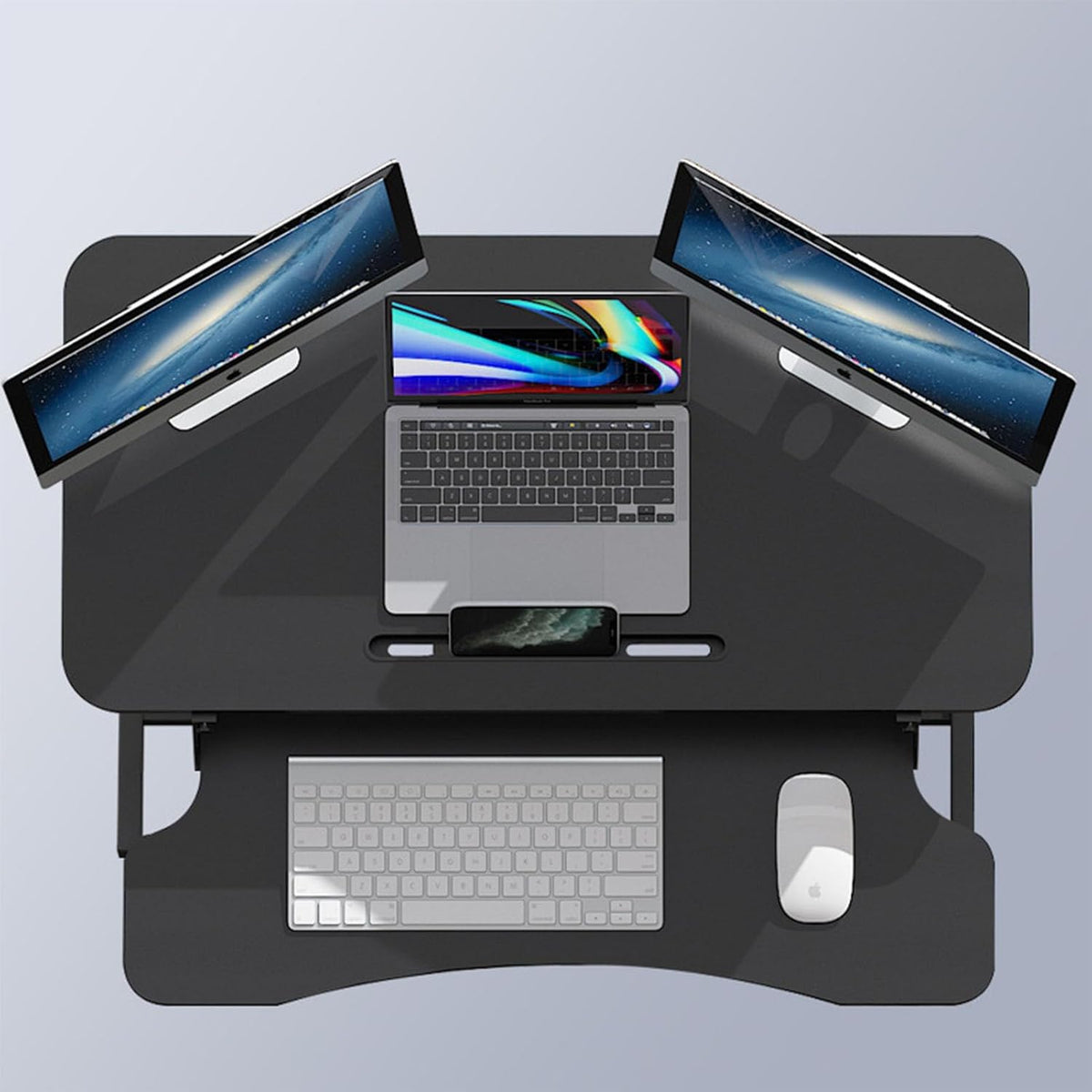 Höhenverstellbarer, schwarzer Schreibtischaufsatz in einem Anwendungsbeispiel mit zwei Bildschirmen, einem Laptop, einer Tastatur und einer Maus von oben